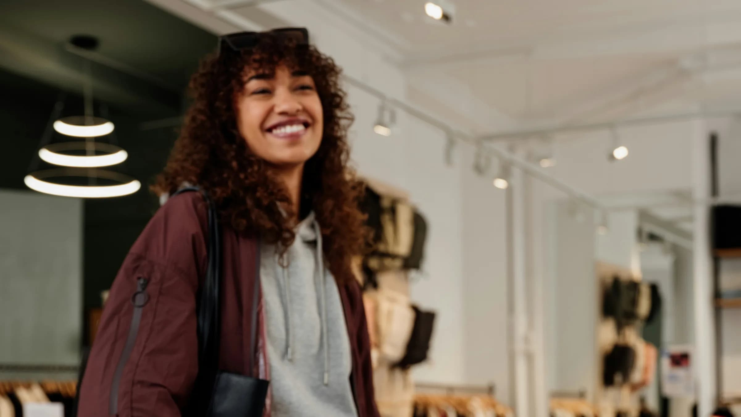 A smiling customer stands at the counter of a bright clothing shop.